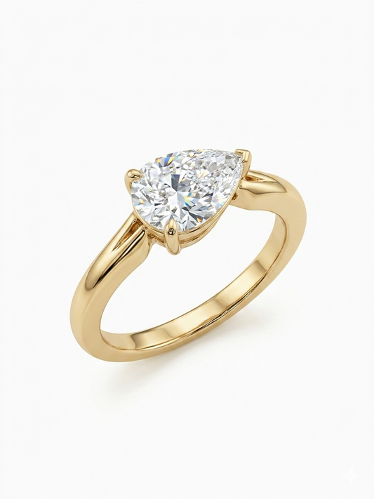 Gold ring with a pear-shaped diamond on a white background